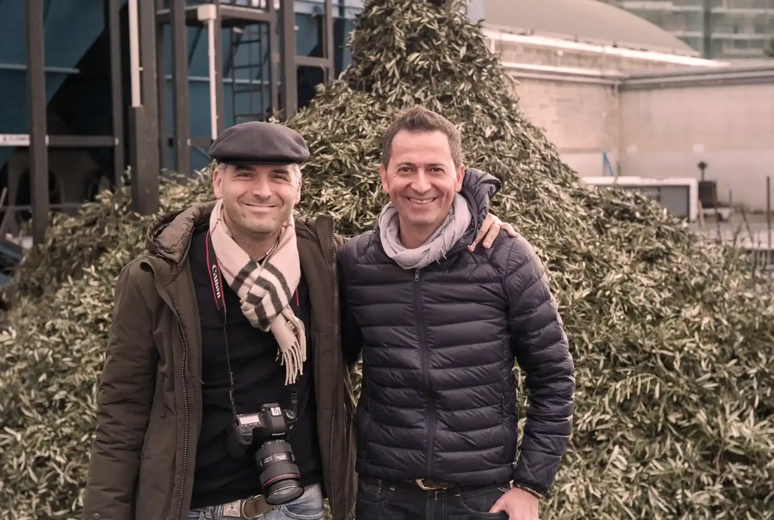 Gianvito Galantino und Maurizio Cortese vor einem Berg Olivenblätter in der Frantoio Galantino.